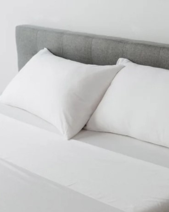 Molecule performance sheet set on bed, close-up of cooling TENCEL and cotton fabric, athlete-endorsed Molecule sheets, wrinkle-resistant breathable sheets, folded Molecule sheet set with pillowcases